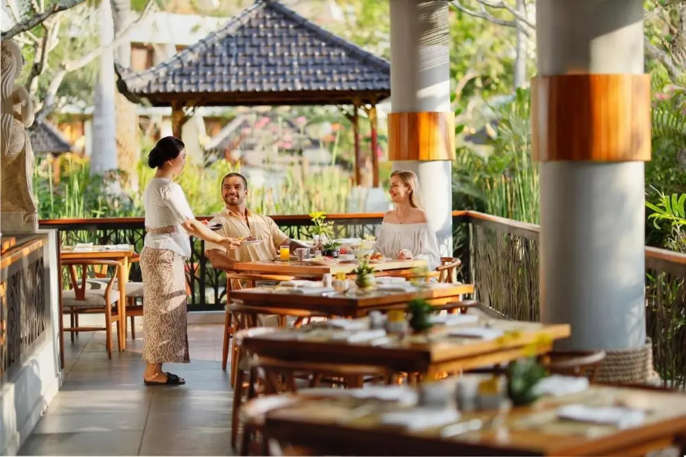 A couple enjoy a meal at an outdoor table at Nusa Dua Beach Hotel & Spa, a Bali resort all-inclusive.