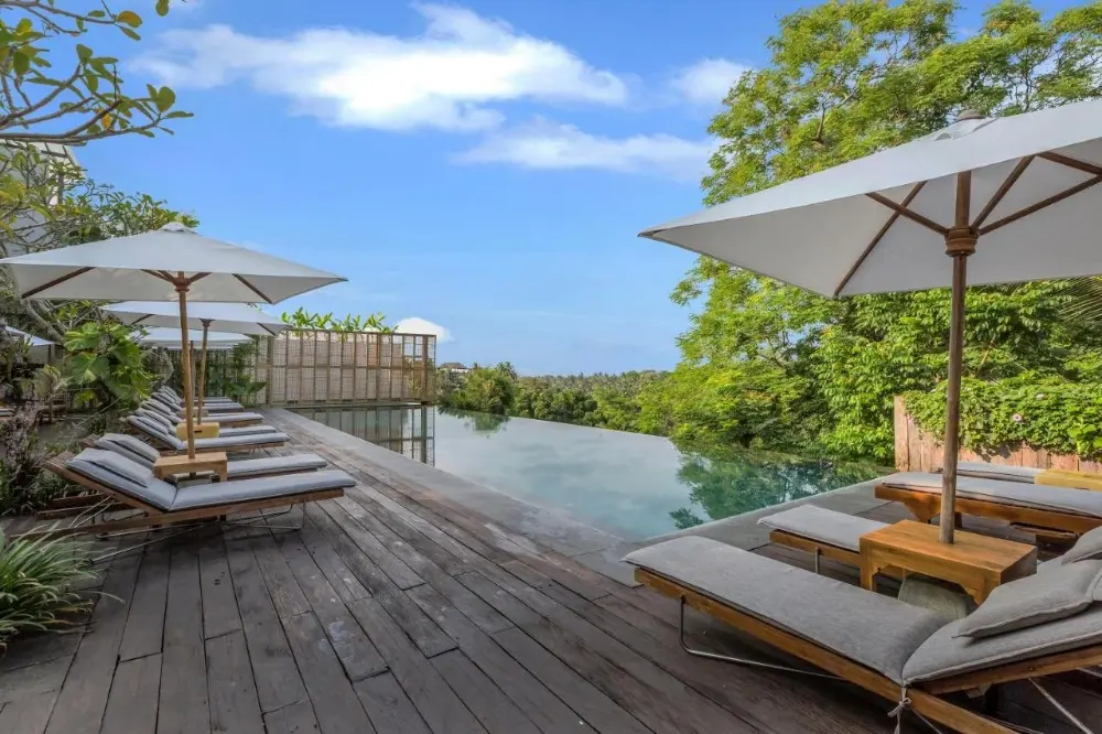 A lovely perspective of a pool at Bisma Eight, highlighting the appeal of a beach resort in Bali surrounded by a natural view.