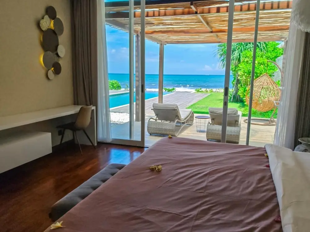 The cosy bedroom at Ketewel Villas and SPA features a beautiful ocean view, ideal for a relaxing stay at a beach resort in Bali.