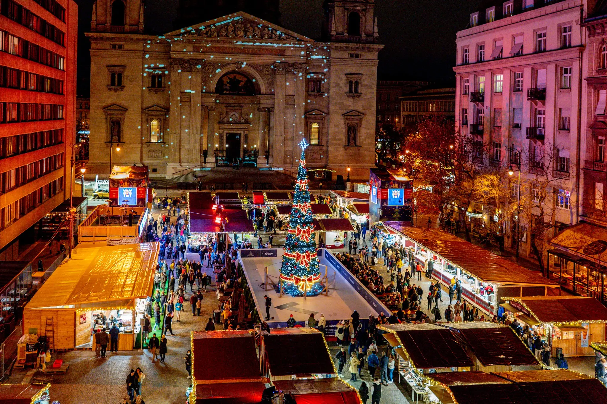 A bustling crowd gathers in a city square, enjoying one of the best Christmas markets in Europe in Budapest, Hungary.