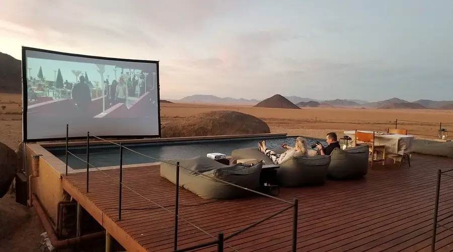 People relaxing on a deck with a projector screen at Zannier Hotels Sonop, one of the best desert hotels worldwide.