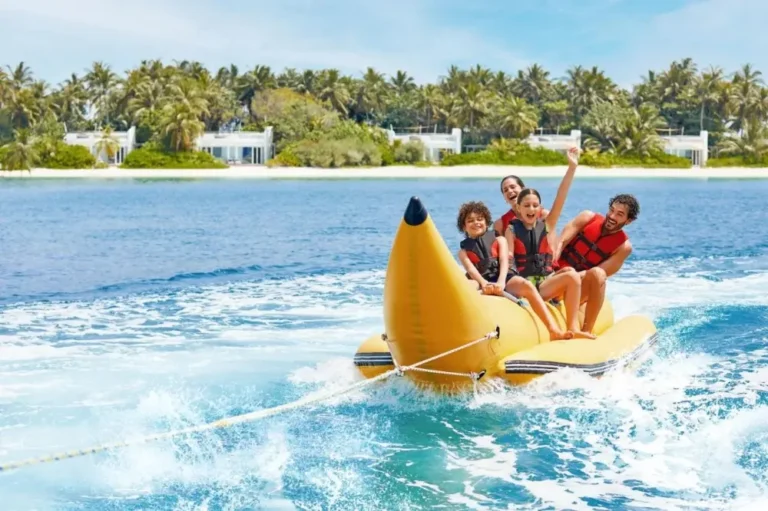 A joyful family enjoying a banana boat ride, surrounded by sunlit waves and a vibrant tropical atmosphere near the best family hotels in Maldives.