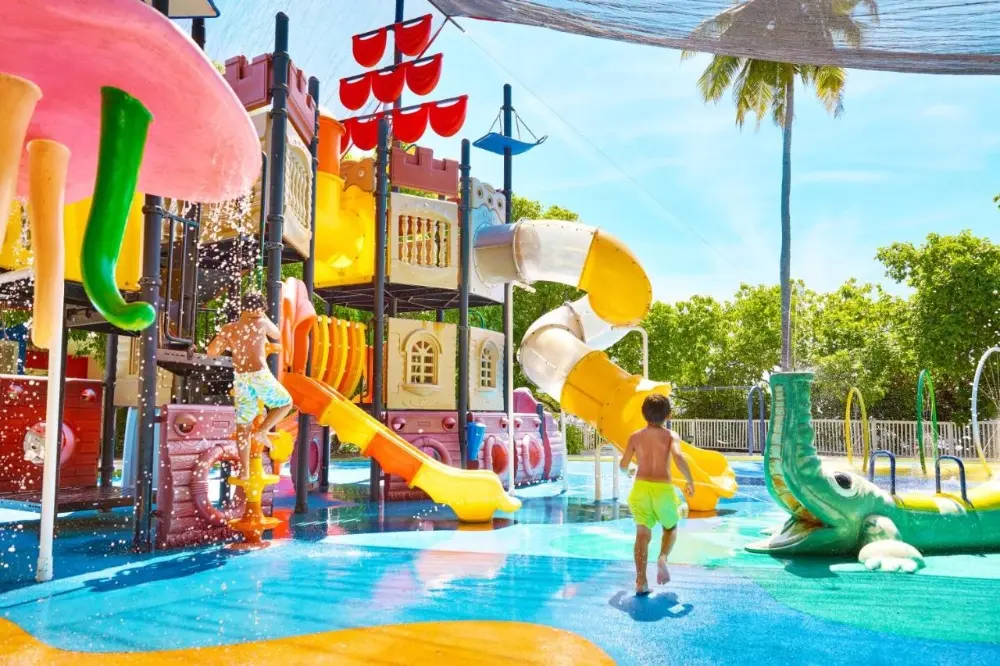 A child joyfully splashes in a water park, surrounded by vibrant slides at Kandima Maldives, a top family hotel in Maldives.