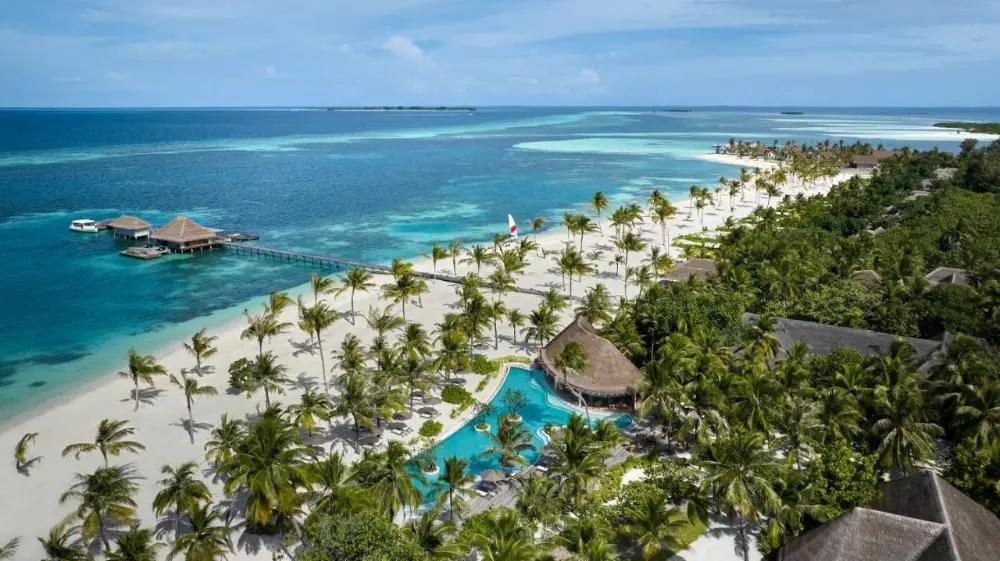 An idyllic view of Six Senses Kanuhura, surrounded by vibrant palm trees and serene waters, perfect as a family hotel in Maldives.