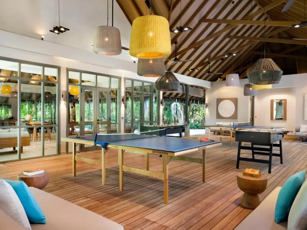 A spacious room featuring ping pong tables and comfortable couches, ideal for family leisure at Vakkaru, a family hotel in Maldives.