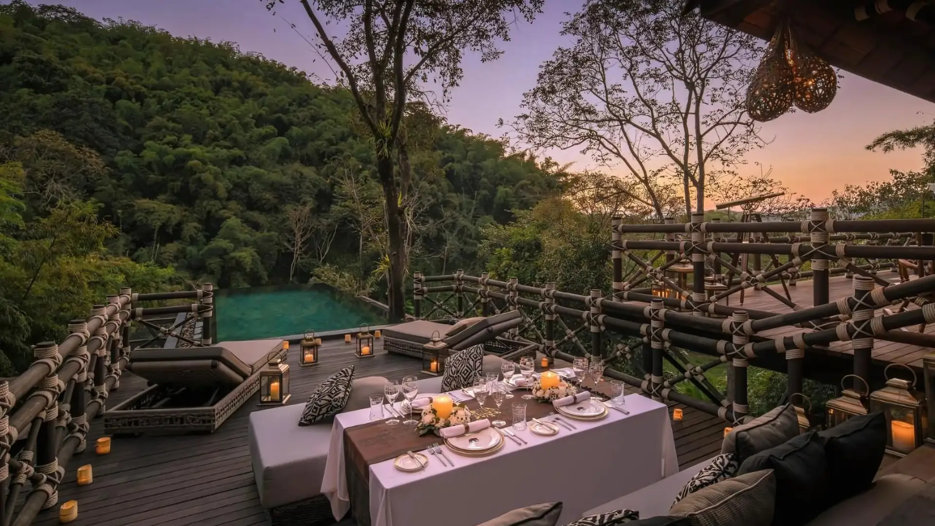 A beautifully set dinner table at Tented Camp Golden Triangle, one of the best Four Seasons hotels in the world, overlooking a stunning pool and lush forest.