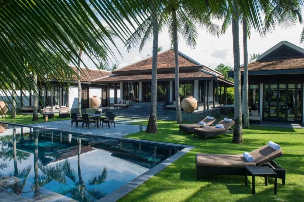 A stunning luxury villa at Four Seasons The Nam Hai, one of the best Four Seasons hotels in the world, featuring a pool and lounge chairs.