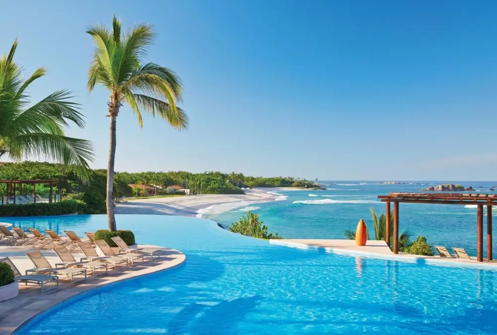 A beautiful pool at Four Seasons Resort Punta Mita, one of the best Four Seasons hotels in the world, surrounded by palm trees.