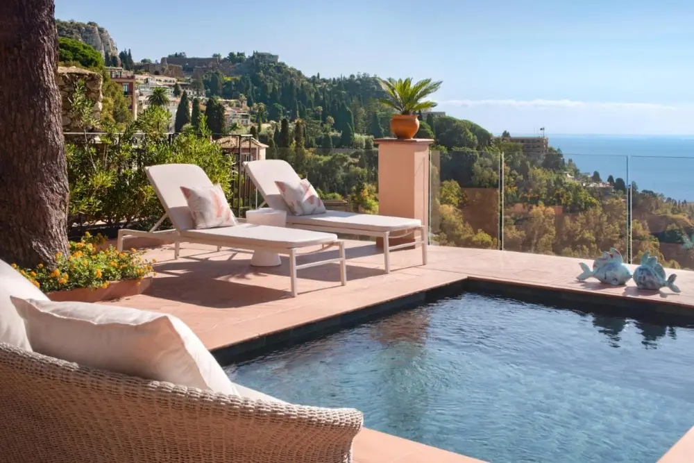 A stunning pool with lounge chairs offers a breathtaking view of the ocean at San Domenico Palace, one of the best Four Seasons hotels in the world.