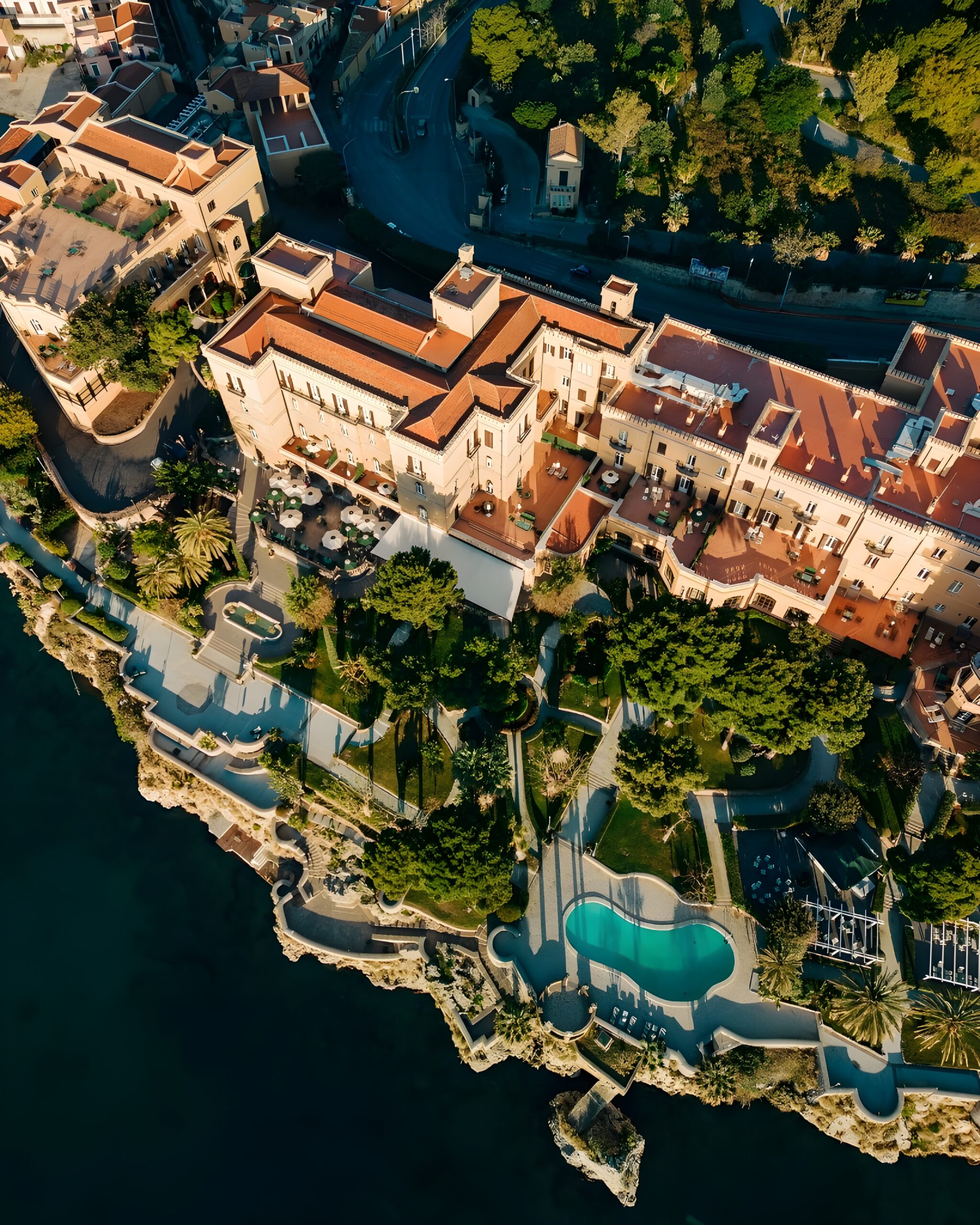 Aerial view of Rocco Forte Villa Igiea perched on a cliff, showcasing the stunning location of this hotel in Sicily with private beach.