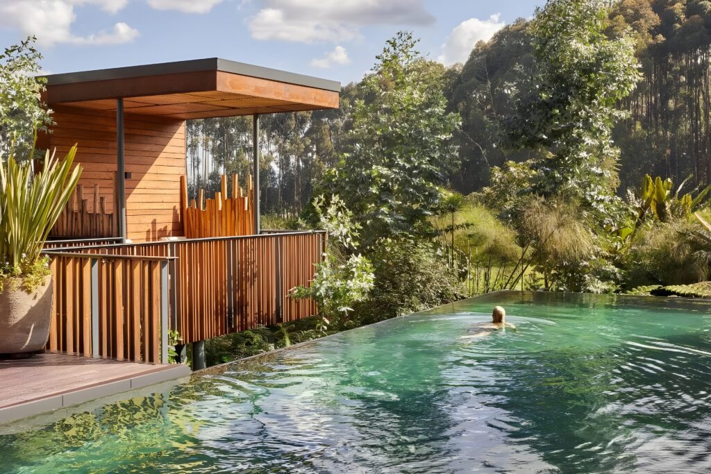 A man swims in a picturesque pool, enveloped by greenery at One&Only Gorilla’s Nest in Rwanda.