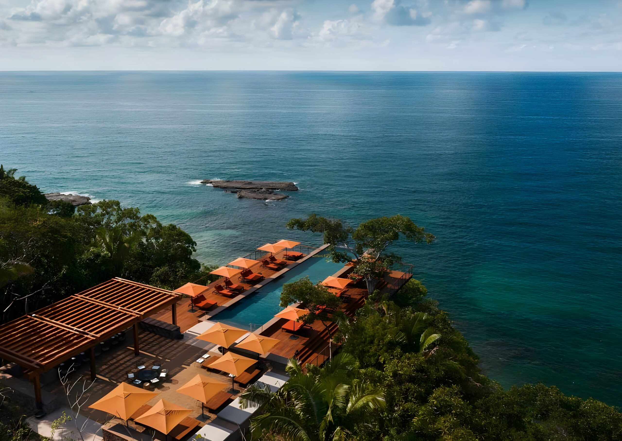 A stunning view of One&Only Mandarina, nestled between lush trees and the ocean in Mexico's picturesque landscape.