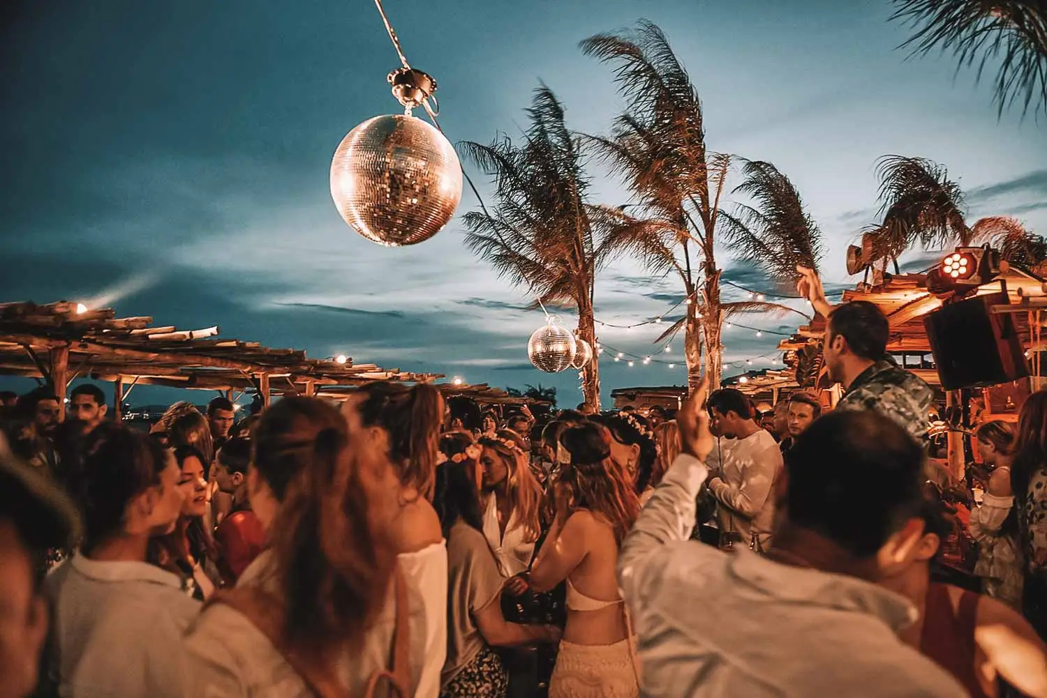 A lively beach party with a crowd enjoying the sun, featuring Poseidon, one of the best hotels in Mykonos for party vibes.