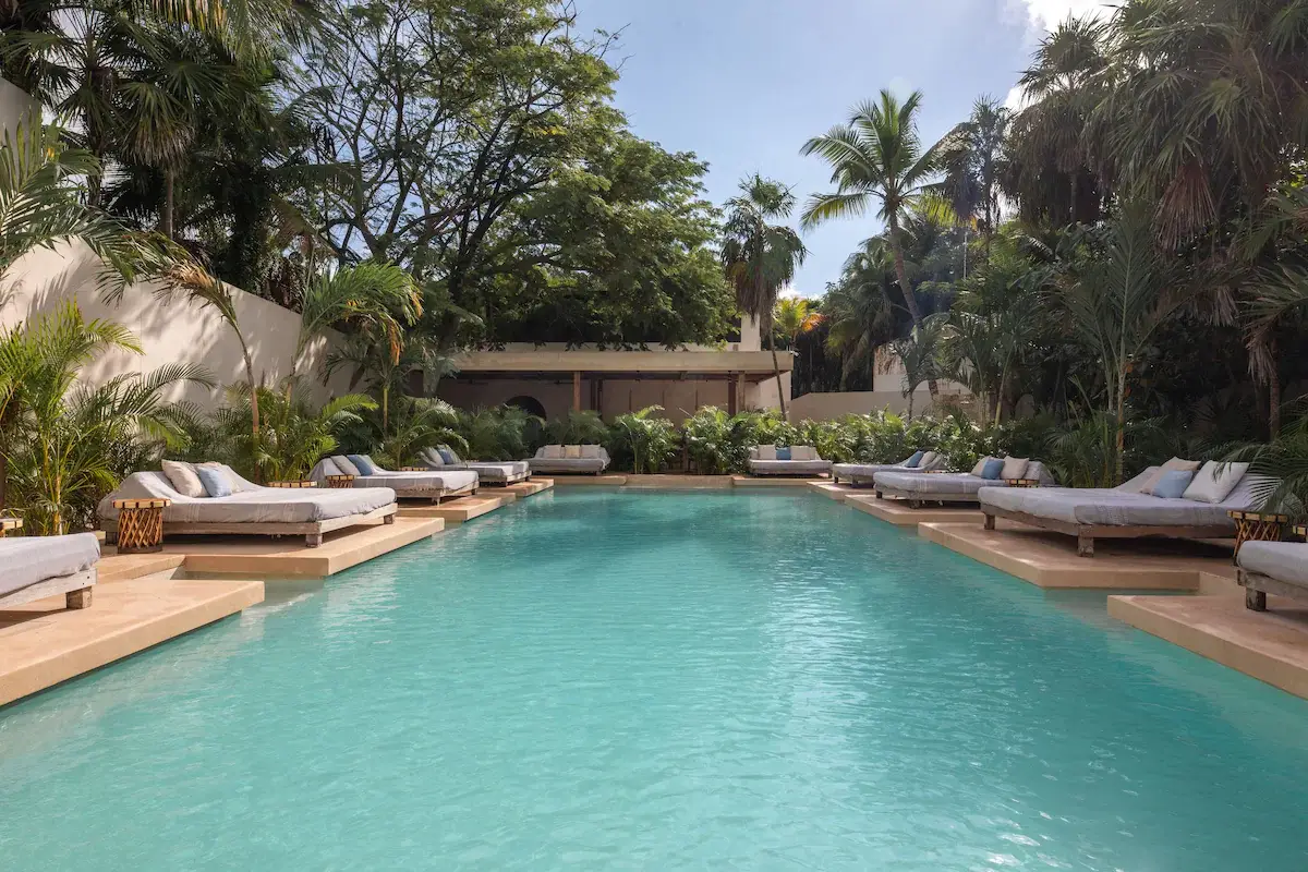 The pool at Ahau Hotel is surrounded by palm trees, perfect for relaxing at one of the best party hotels in Tulum.