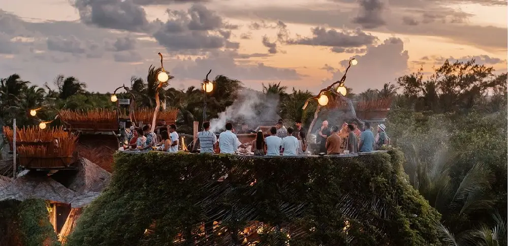 A group of friends enjoying a sunset on a platform, perfect for a stay at Azulik, one of the best party hotels in Tulum.