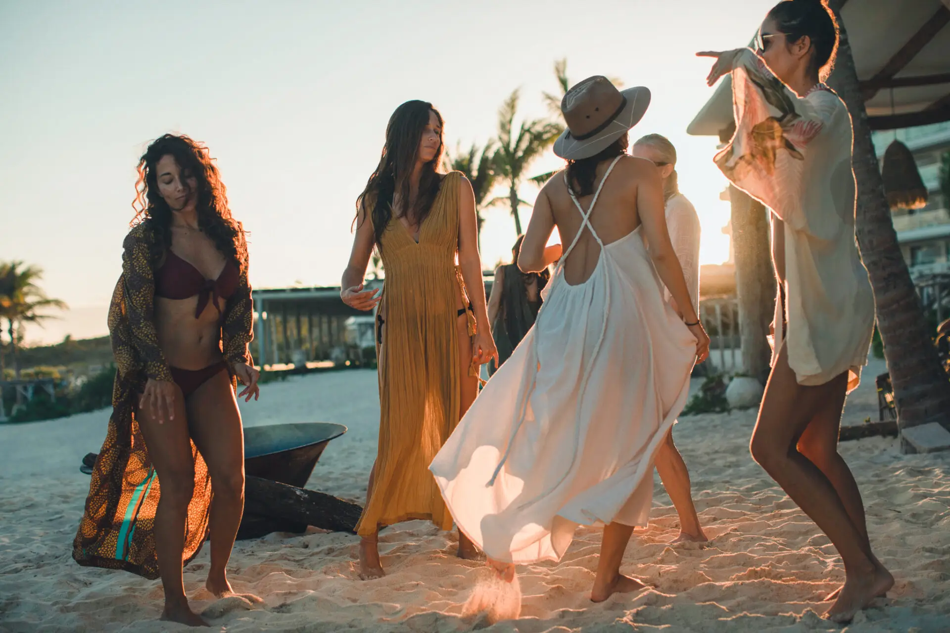 Four women joyfully dancing on the beach at sunset, celebrating life near Palmaïa, one of the best party hotels in Tulum.