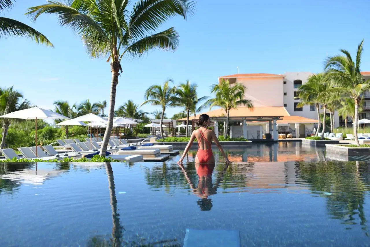 A woman in a red swimsuit enjoys the pool at Unico Hotel Riviera Maya, one of the best party hotels in Tulum.