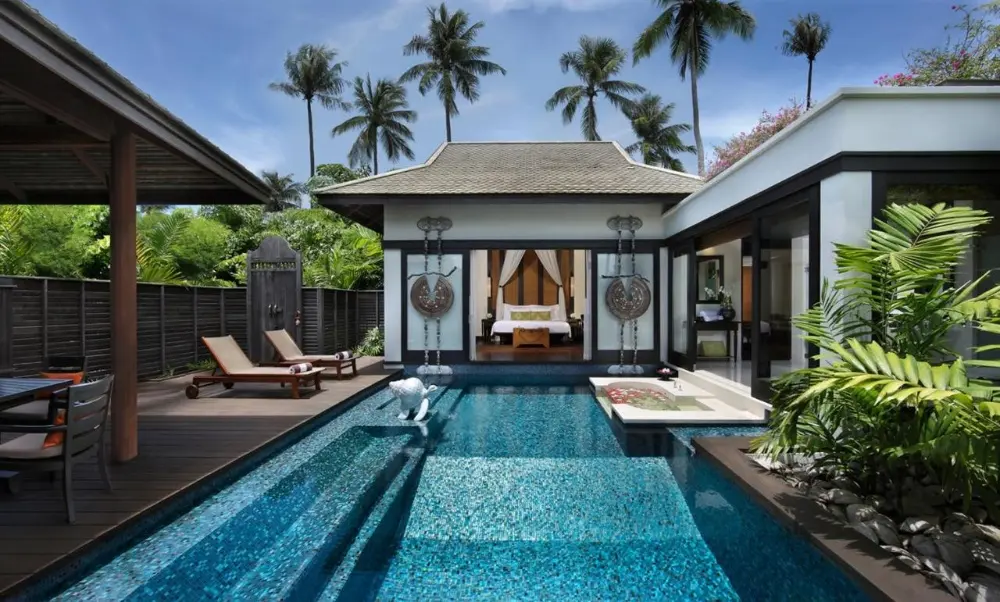 A tranquil poolside scene at Anantara Mai Khao Villas, ones of the best resorts in Phuket, showcasing lounge chairs and umbrellas for leisure and shade.