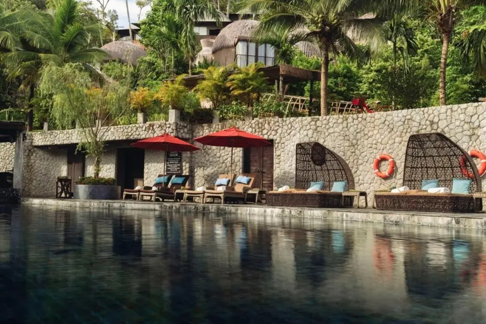 A peaceful poolside at Keemala Resort in Phuket, complete with lounge chairs and umbrellas for sun-soaked relaxation.