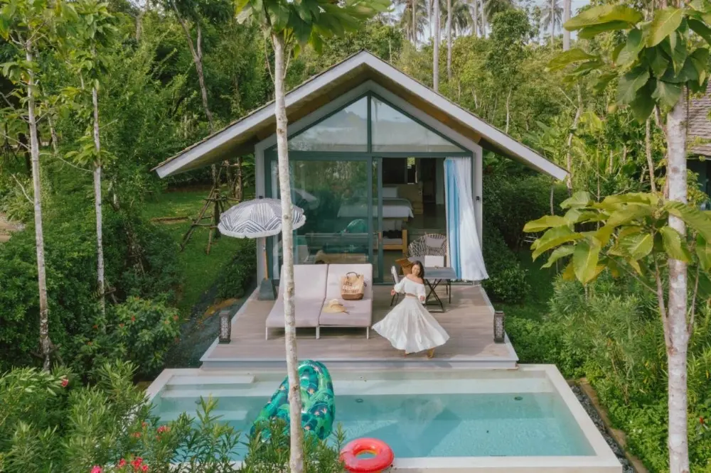 A woman in a white dress stands by the pool at Island Escape Burasari, one of the best resorts in Phuket for couples.