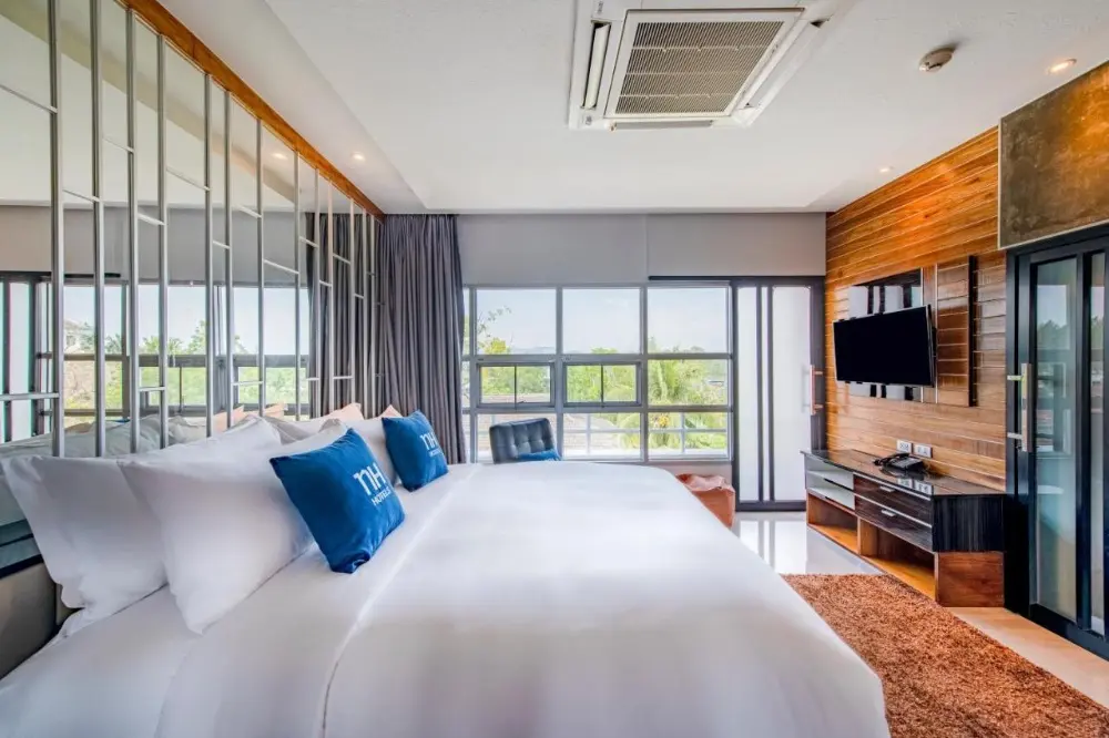 A cosy hotel room at NH Boat Lagoon featuring a large bed and television, perfect for couples looking for one of the best resorts in Phuket.