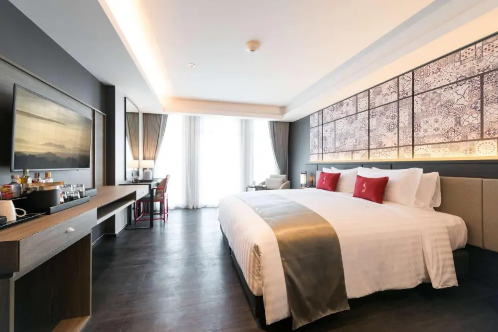 A cosy hotel room at Ramada Plaza featuring a large bed and television, perfect for couples exploring the best resorts in Phuket.