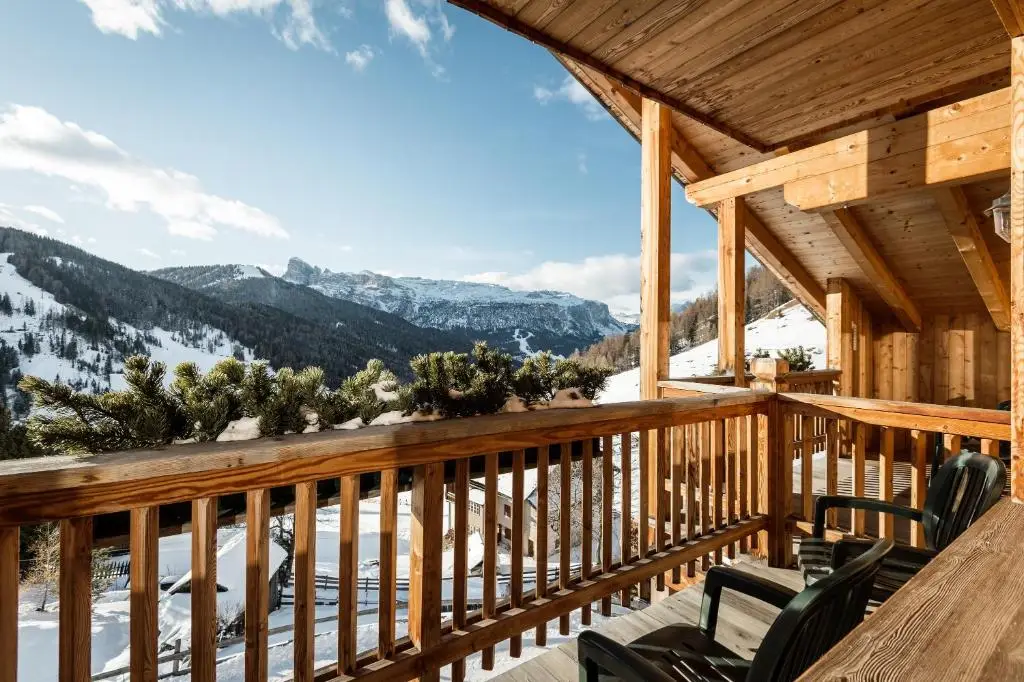 Enjoy the mountain view from the balcony of Hotel Ciasa Salares, featuring chairs, a great spot among the best ski hotels in Italy.