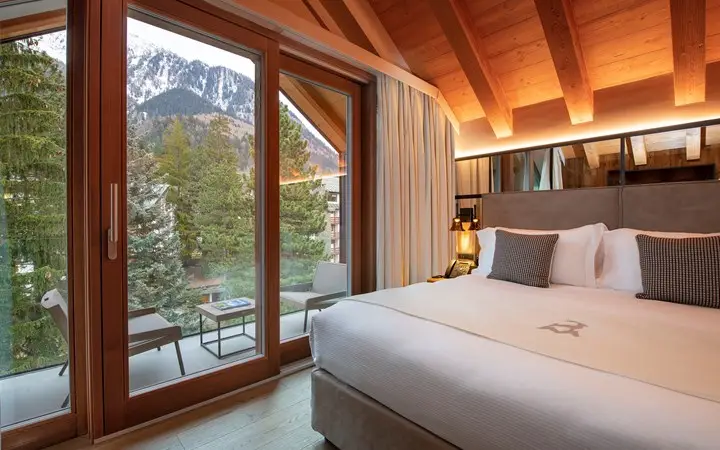 Cozy bedroom at Le Massif with stunning mountain views, perfect for relaxing at one of the best ski hotels in Italy.