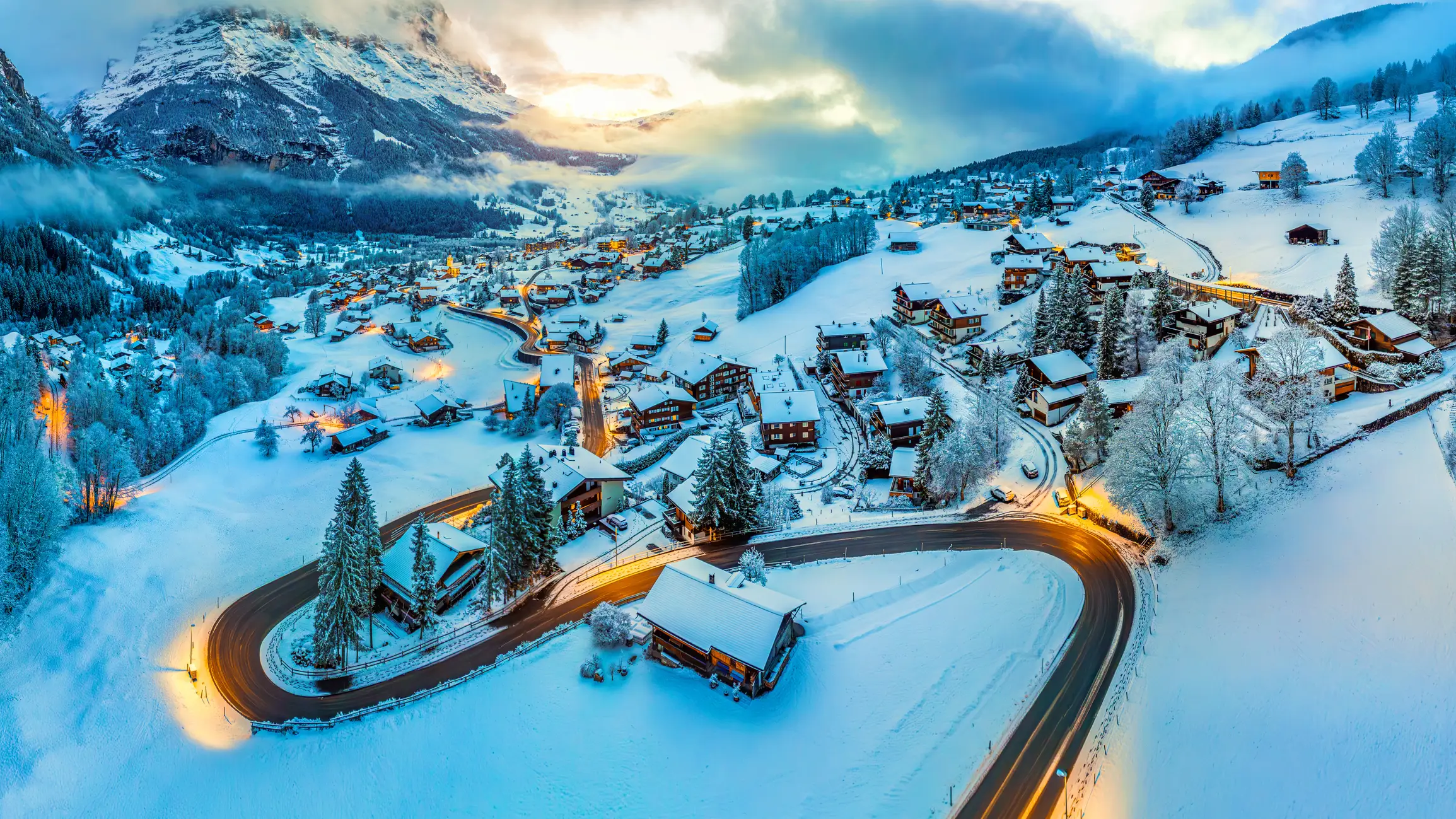 A snowy mountain village in Grindelwald, with a winding road, showcasing it is one of the best ski resorts in Switzerland.