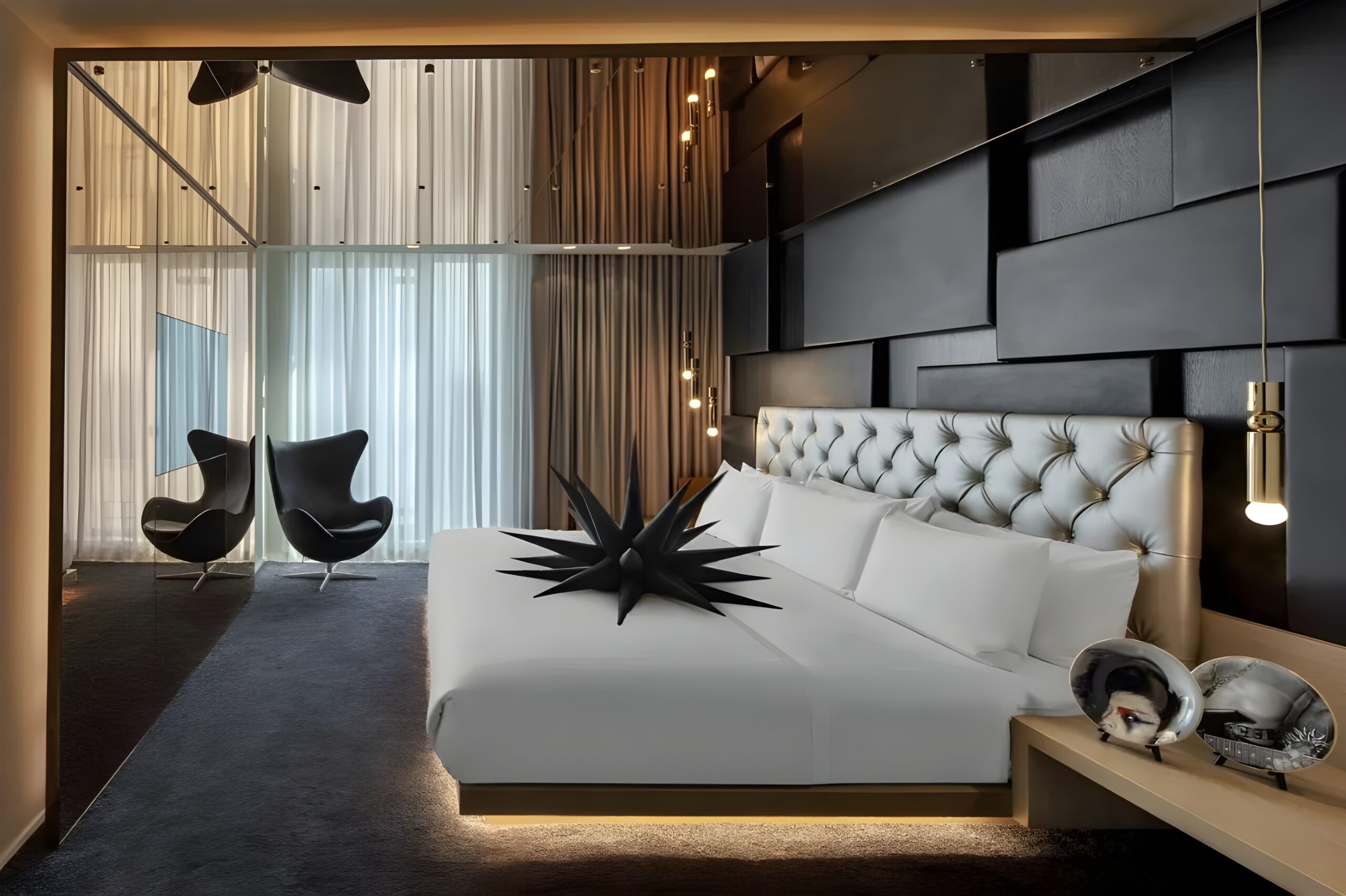 A stylish hotel room featuring a comfortable bed and a chic chair, showcasing W London - Leicester Square's, one of the best W hotels in the world with modern design.