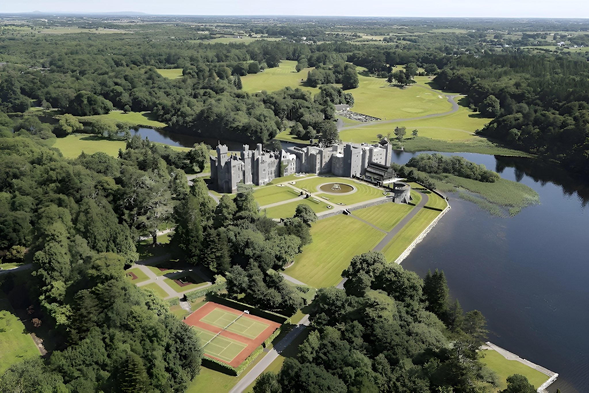 Stunning aerial perspective of Ashford Castle, Ireland, enveloped by vibrant trees, highlighting its majestic architecture as one of the best castles in the world.