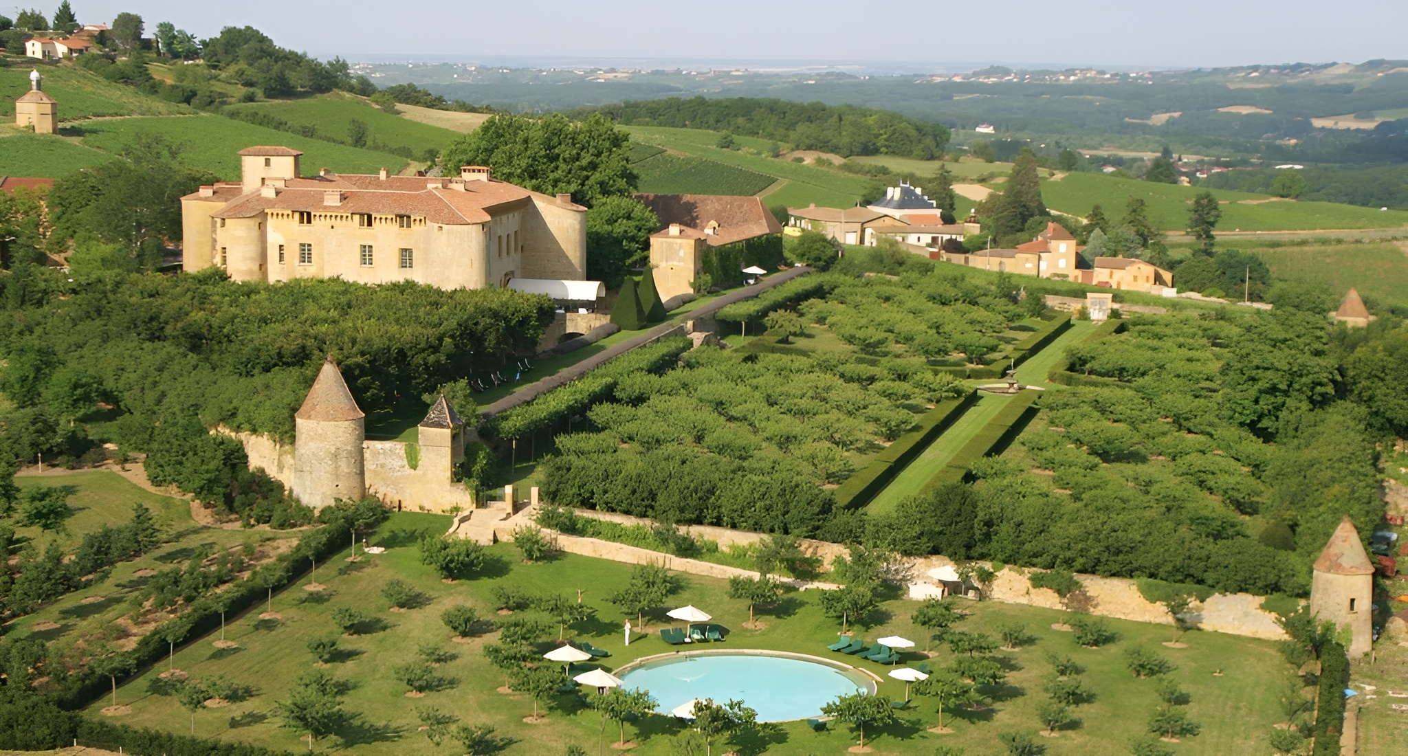 Aerial shot of Château de Bagnols, one of the best castle hotels in the world displaying a vast estate with a luxurious pool set in a picturesque French countryside.