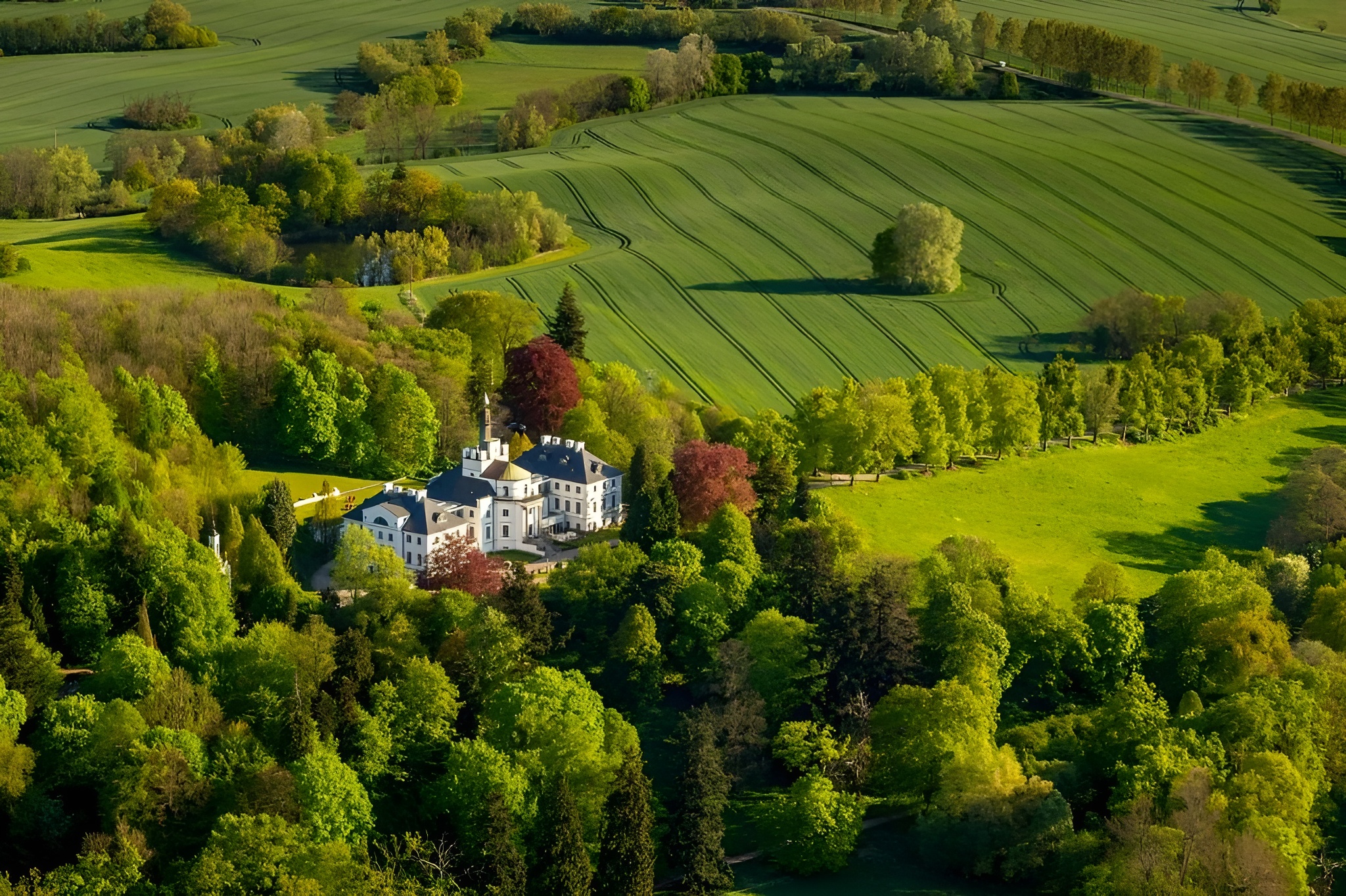 Aerial shot of one of the best castle hotels in the world, Schlosshotel Burg Schlitz, embraced by expansive green fields.