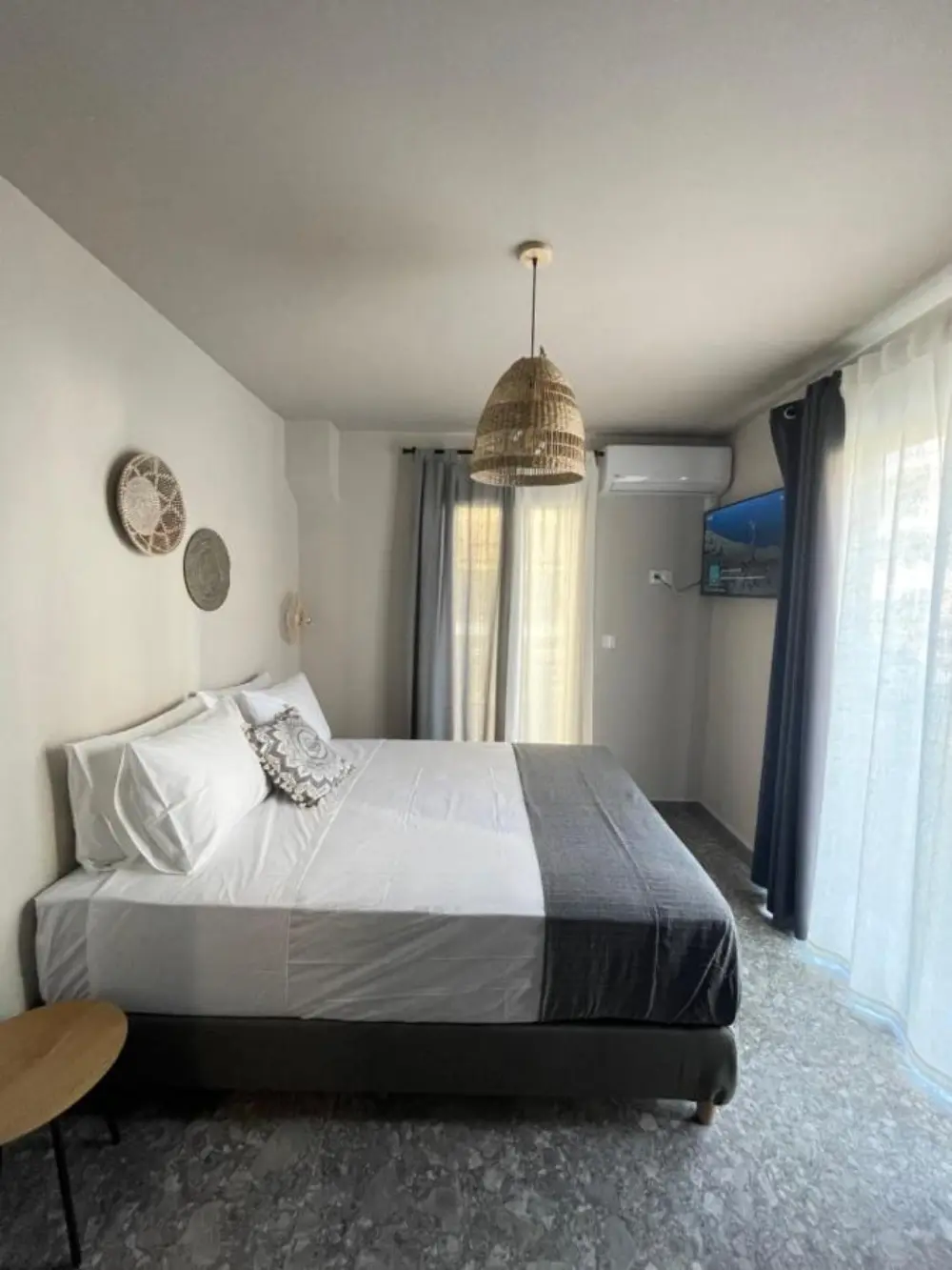 A cosy bedroom featuring a bed, showcasing the elegance of the design hotel in Santorini Istoria Hotel.