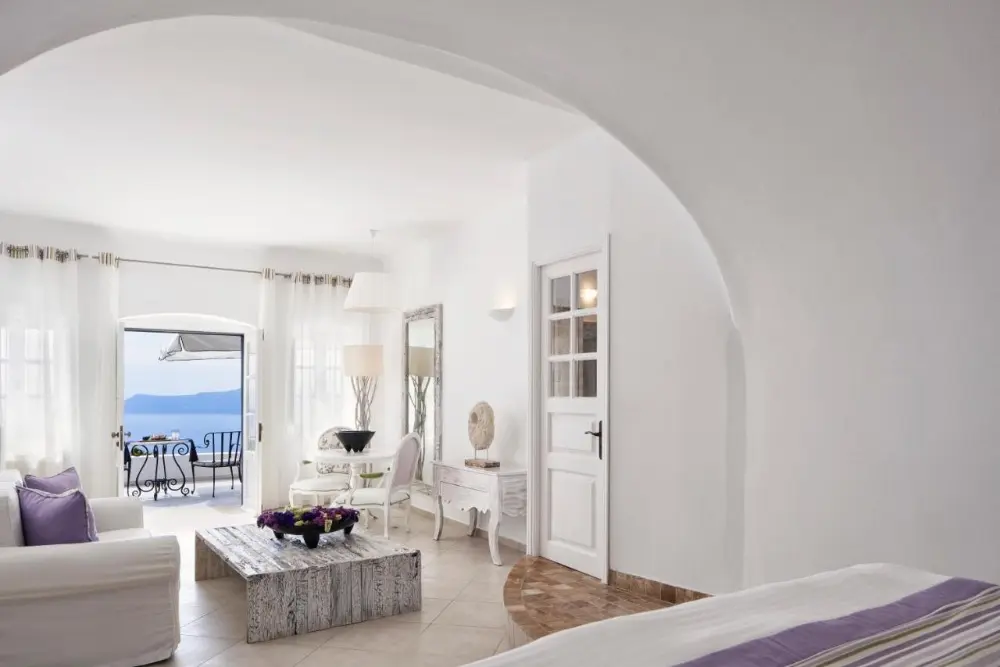 A stunning white bedroom at San Antonio, a design hotel in Santorini, showcasing a breathtaking ocean view.