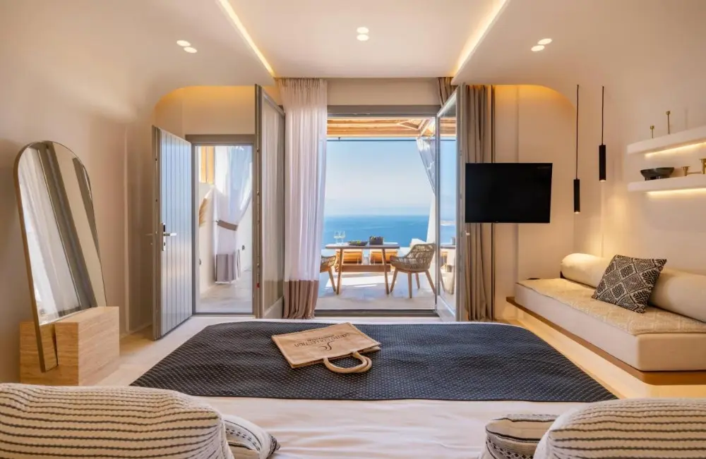 The bedroom at Santo Mine Oia Suites, a design hotel in Santorini, offers a cosy bed and breathtaking ocean views.