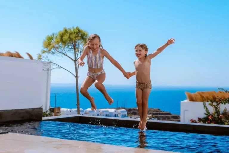 Two kids jumping into the swimming pool of a family friendly hotel in Santorini