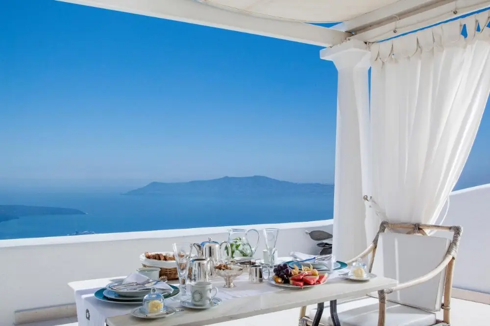 A balcony table with ocean views at Tsitouras Collection, a family-friendly hotel in Santorini, perfect for dining and relaxation.