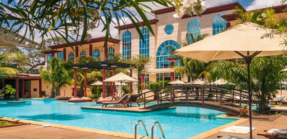 A luxurious hotel pool featuring a charming small bridge and elegant umbrellas, exemplifying a hotel that excludes making marketing mistakes.