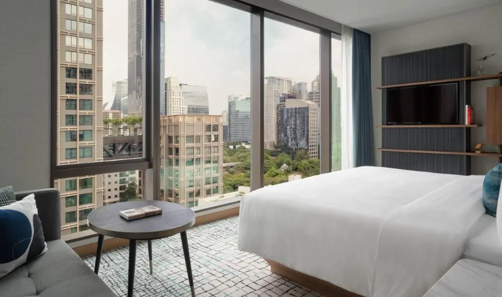 A luxurious hotel room at Kimpton Maa-Lai in Bangkok, Thailand, offering a stunning view of the city skyline.