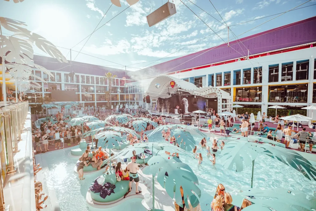 A crowded beach club pool, filled with people enjoying the lively atmosphere typical of party hotels in Ibiza.