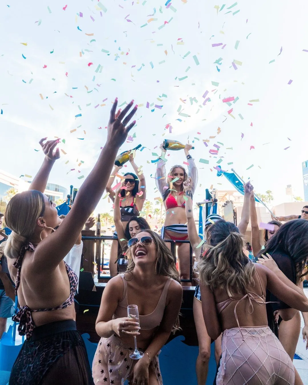 Women in colorful bikinis and hats celebrate by tossing confetti at the MGM Grand Resort and Casino, a party hotel in Las Vegas.