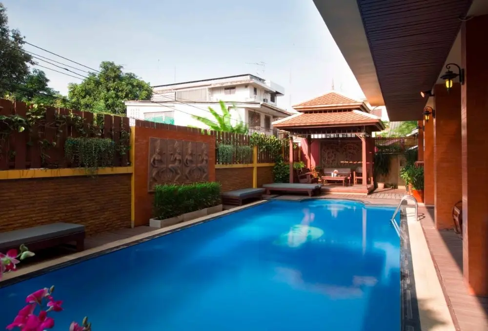 A cosy backyard pool surrounded by a wooden fence, featuring the charm of a romantic hotel in Bangkok, Lamphu Tree House.