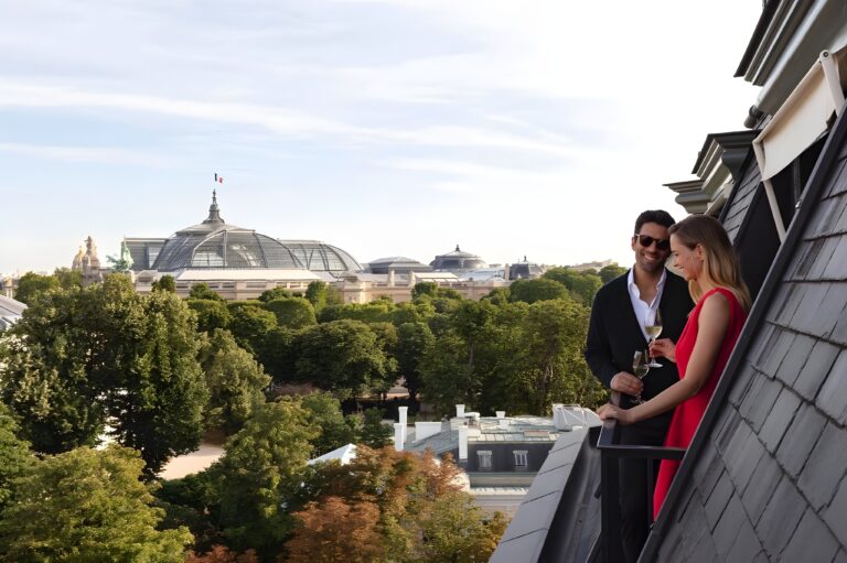 A couple enjoys a romantic hotel in Paris on a balcony with a stunning view of the Eiffel Tower.