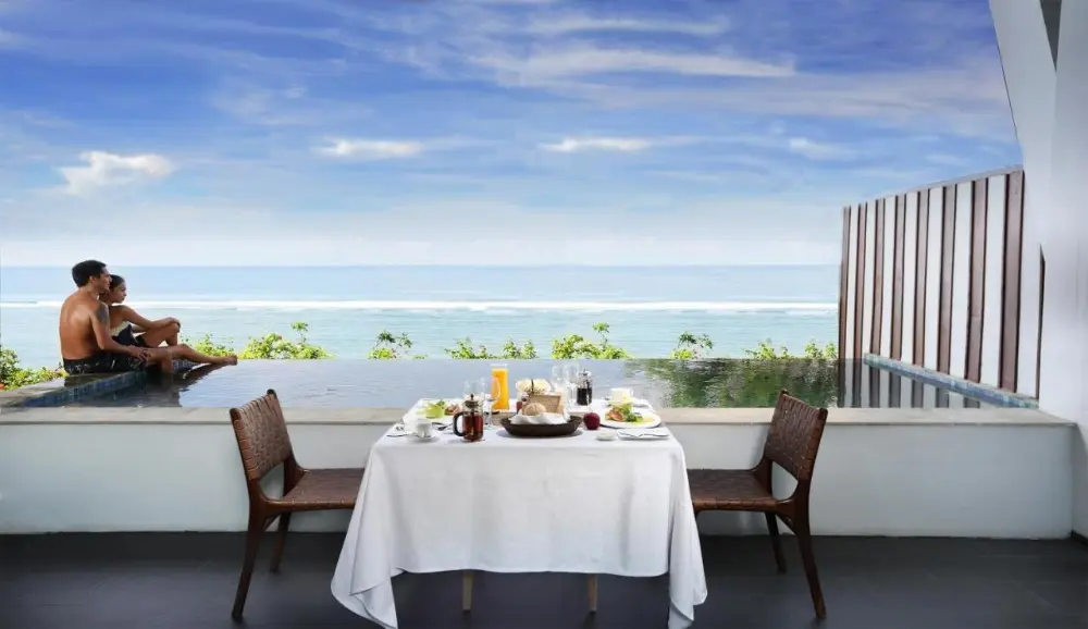 A couple dining at a table with a stunning ocean view, a lovely experience at a Bali resort all-inclusive.