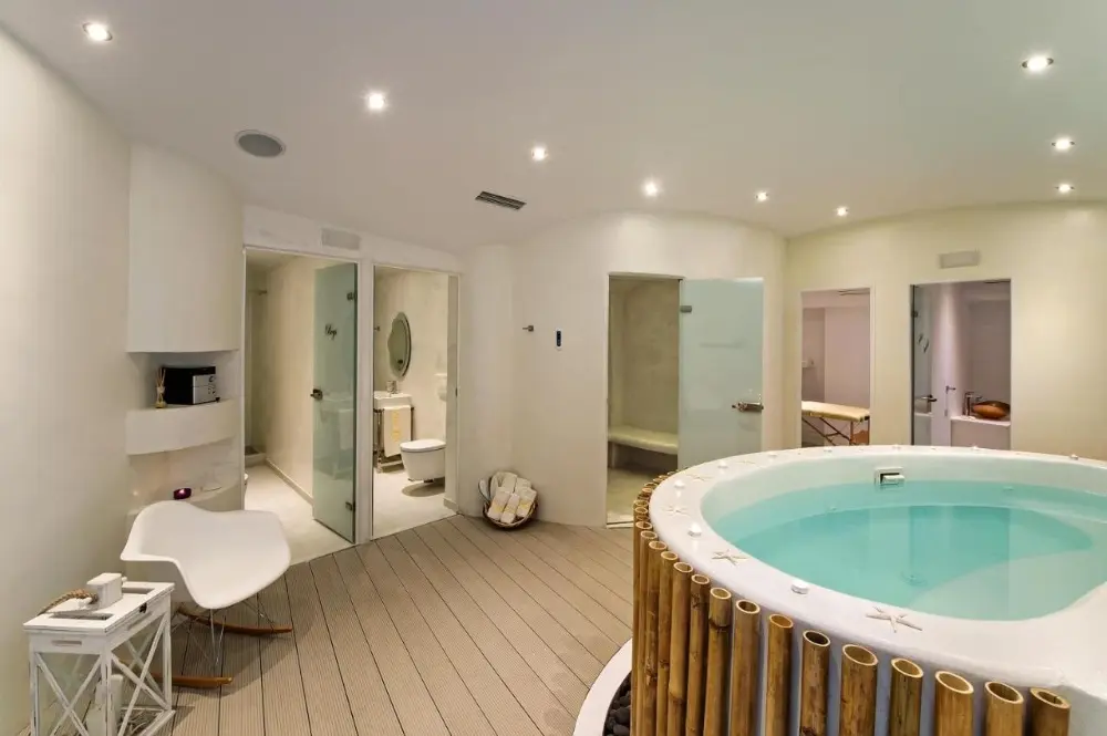 A luxurious bathroom featuring a large tub and shower, ideal for relaxation at Ira, one of the best spa hotels in Santorini.