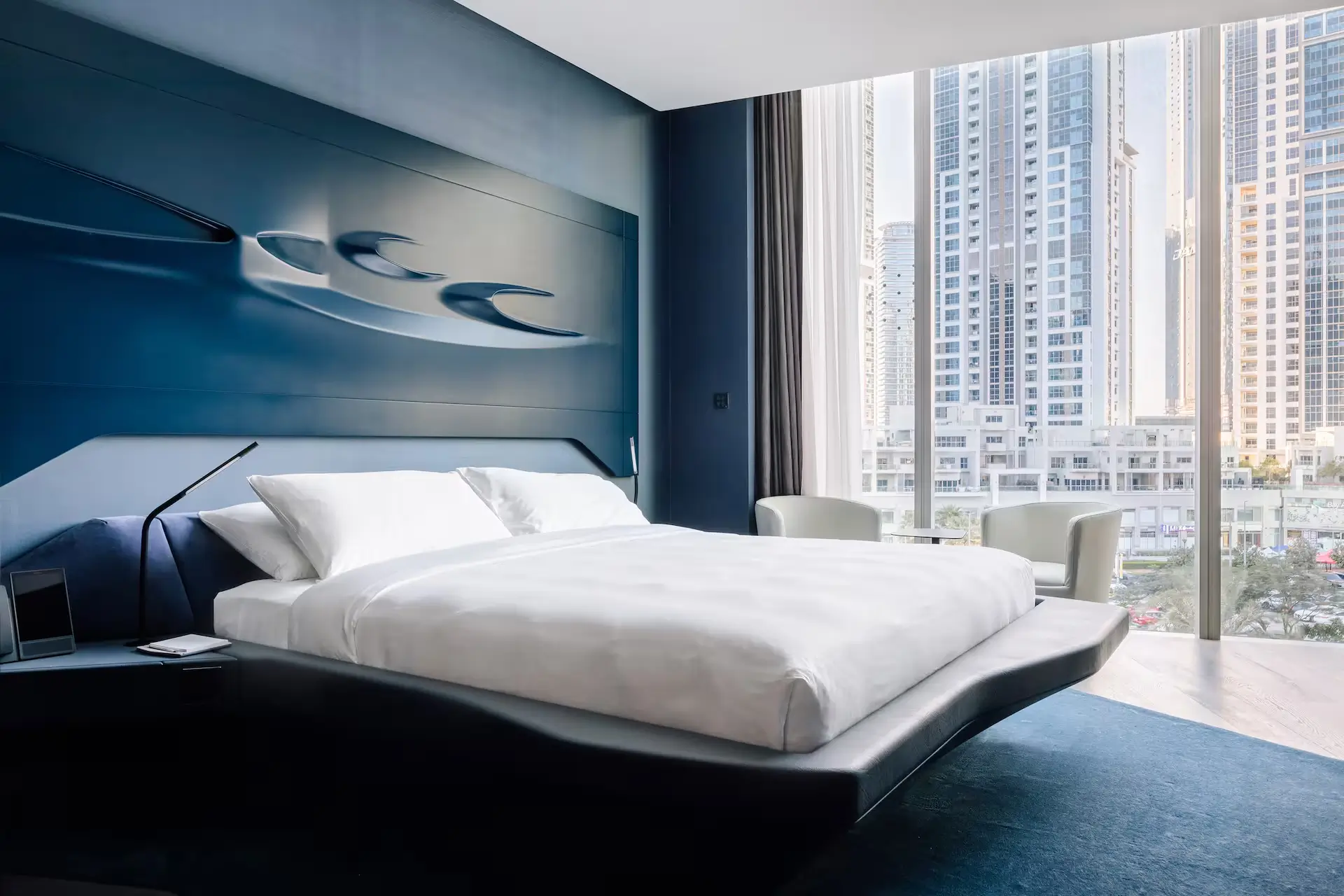 A modern bedroom featuring blue walls and a stylish bed, located in the Opus ME Dubai Hotel, a design hotel in Dubai.