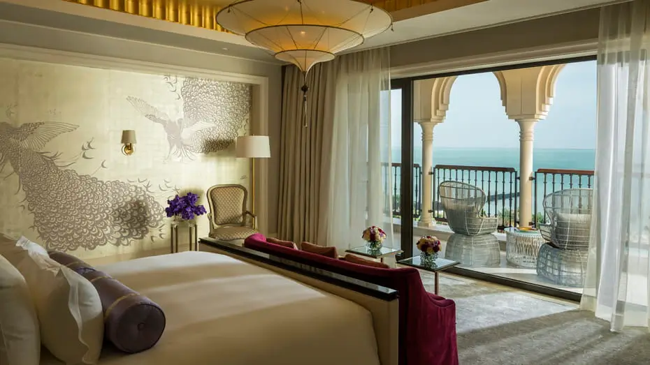 A luxurious bedroom at the Four Seasons, luxury hotel in Dubai, featuring an ocean view and a private balcony overlooking Jumeirah Beach.