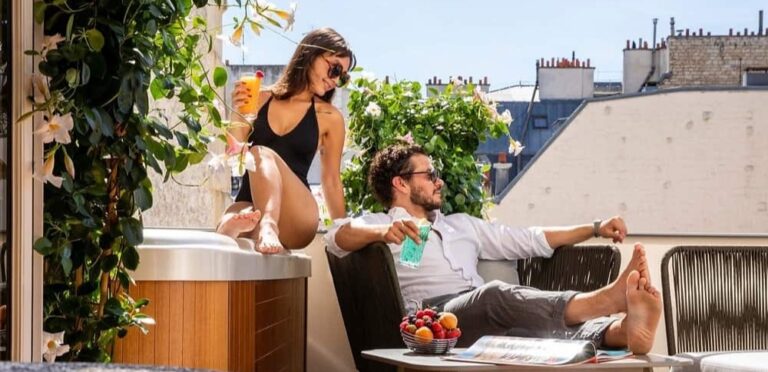 A couple relaxes on a balcony with a city view, thanks to the hotel using AI in its marketing.