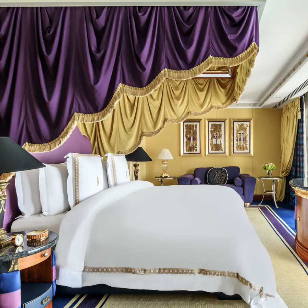 A luxurious bedroom featuring purple and gold curtains, complemented by an elegant bed, at the Jumeirah Burj Al Arab, luxury hotel in Dubai